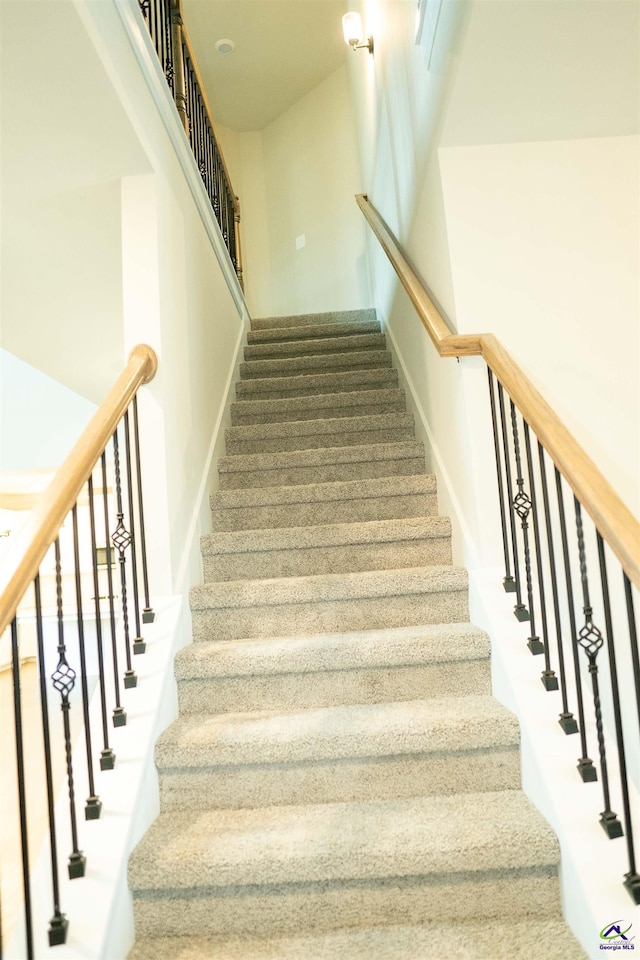 hall featuring light colored carpet, baseboards, an upstairs landing, and attic access