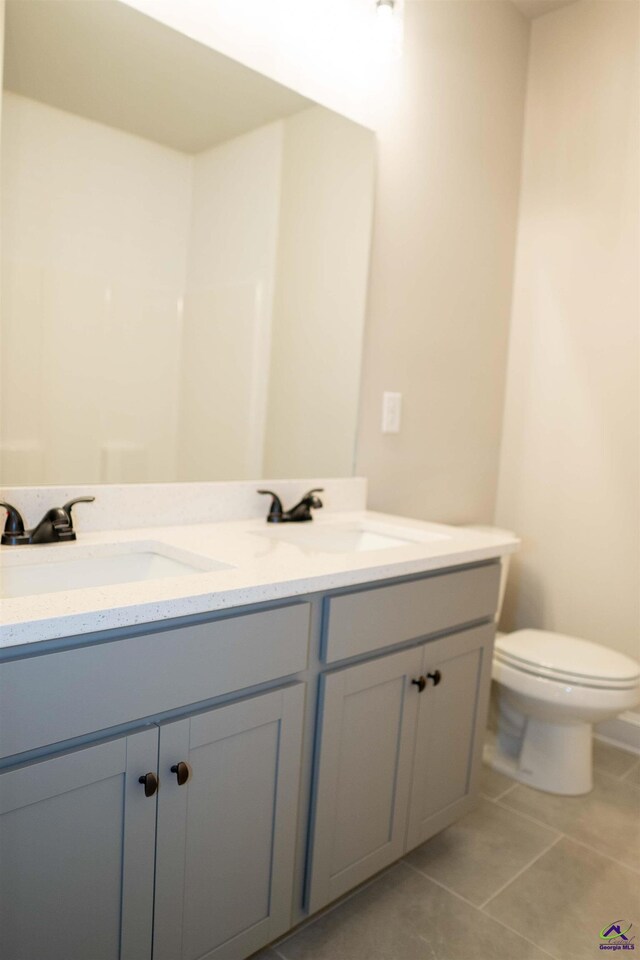 bathroom with tile patterned flooring, a sink, and double vanity