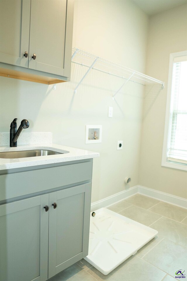 clothes washing area featuring baseboards, a sink, arched walkways, and light carpet