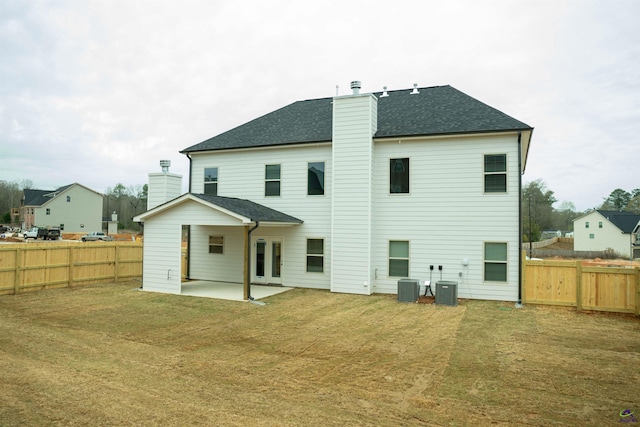 rear view of house with central air condition unit, a patio, a chimney, and a fenced backyard