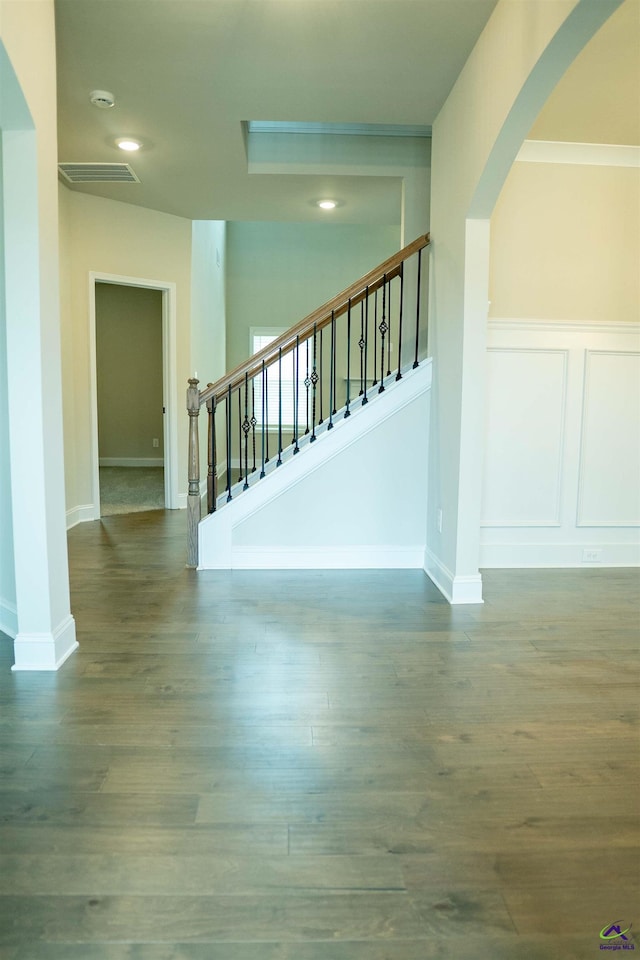 unfurnished dining area featuring a tray ceiling, arched walkways, a decorative wall, and a chandelier