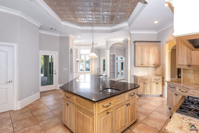 kitchen featuring crown molding, a kitchen island with sink, and a tray ceiling