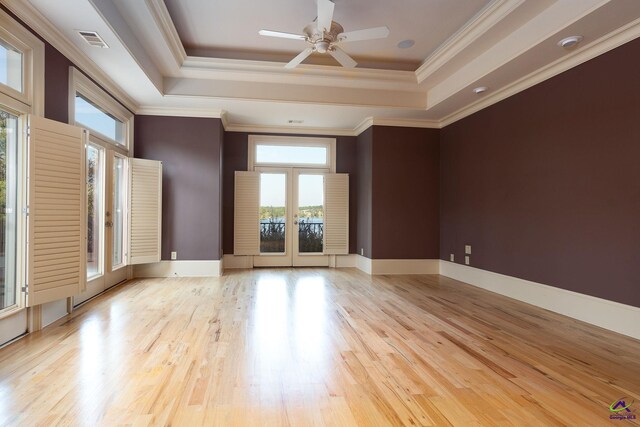 unfurnished room featuring crown molding, a tray ceiling, light hardwood / wood-style floors, and ceiling fan