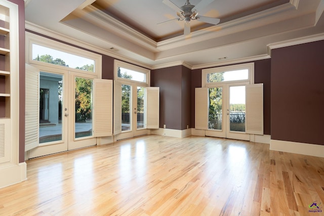 spare room featuring french doors, a raised ceiling, ornamental molding, and light wood-type flooring