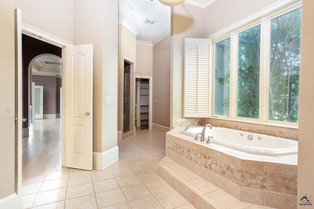 bathroom with ornamental molding, tiled tub, and tile patterned floors