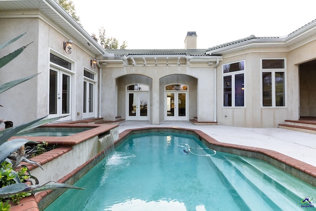 view of swimming pool with a patio, french doors, pool water feature, and an in ground hot tub