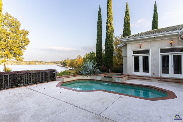 view of pool with a patio area, an in ground hot tub, a water view, and french doors