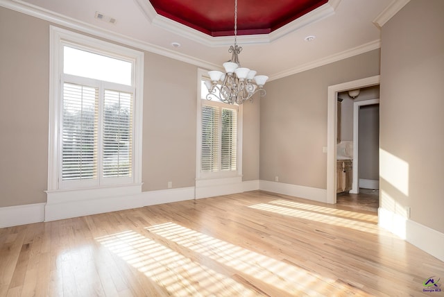 unfurnished dining area featuring crown molding, a chandelier, light wood-type flooring, and a raised ceiling