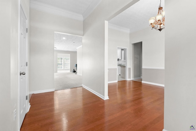 empty room with ornamental molding, hardwood / wood-style flooring, and an inviting chandelier