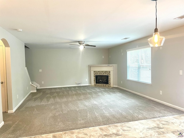 unfurnished living room with visible vents, carpet floors, baseboards, ceiling fan, and a tiled fireplace