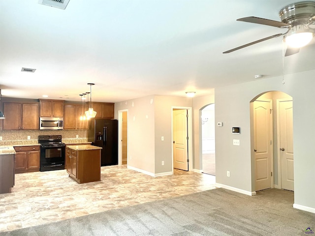 kitchen with arched walkways, a ceiling fan, a kitchen island, visible vents, and black appliances