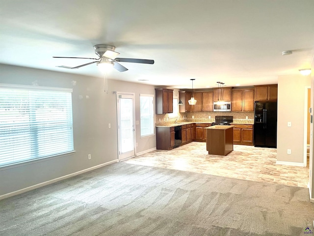 kitchen with light colored carpet, a ceiling fan, open floor plan, baseboards, and black appliances