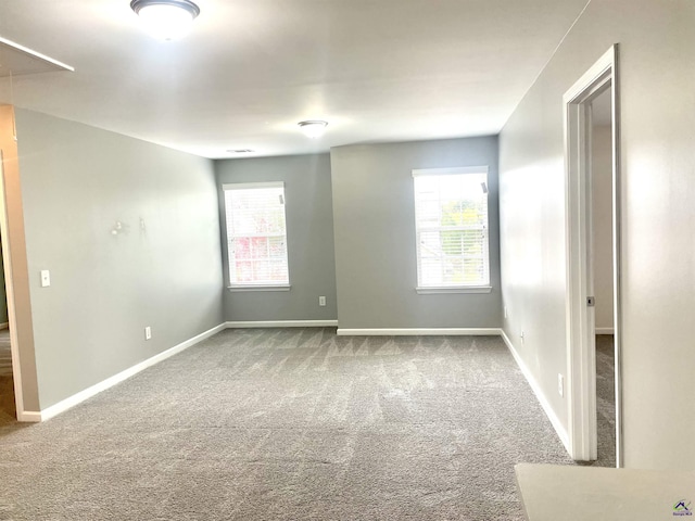 spare room featuring baseboards, a healthy amount of sunlight, and carpet