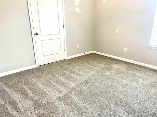 carpeted spare room featuring baseboards