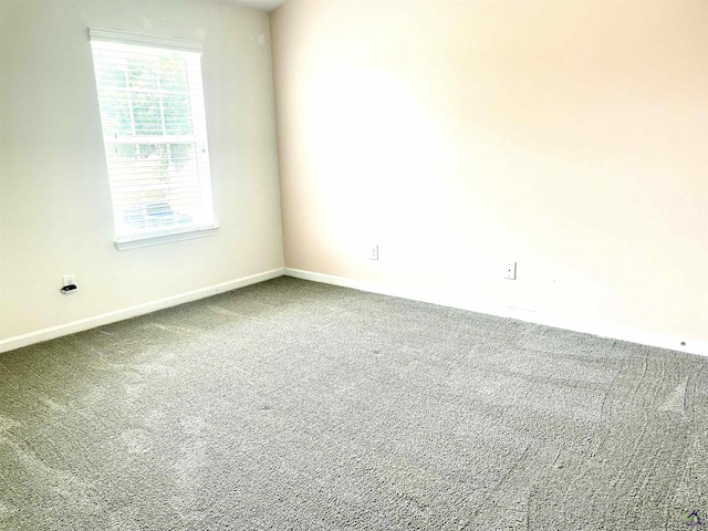 carpeted spare room featuring baseboards