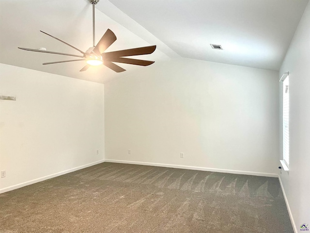 spare room featuring ceiling fan, visible vents, vaulted ceiling, baseboards, and dark colored carpet