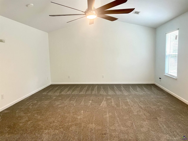 spare room with a ceiling fan, visible vents, lofted ceiling, and dark colored carpet