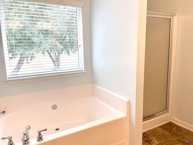 bathroom featuring a garden tub, baseboards, and a stall shower
