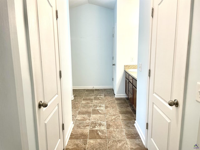 bathroom with baseboards, stone finish flooring, lofted ceiling, and vanity