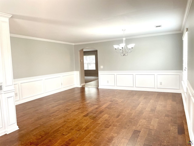 unfurnished room with ornamental molding, a decorative wall, a chandelier, hardwood / wood-style flooring, and arched walkways