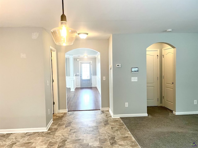 unfurnished room with arched walkways and baseboards
