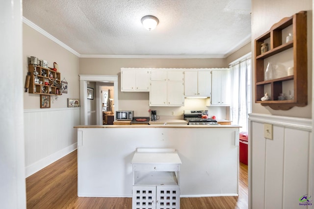 kitchen with crown molding, appliances with stainless steel finishes, light hardwood / wood-style flooring, and white cabinets