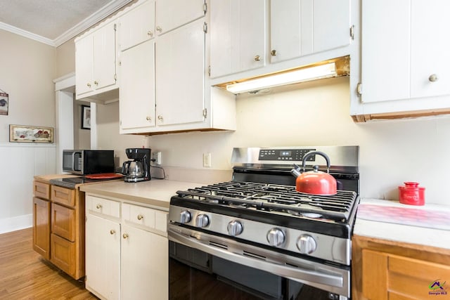 kitchen with a textured ceiling, light hardwood / wood-style floors, stainless steel appliances, white cabinets, and ornamental molding