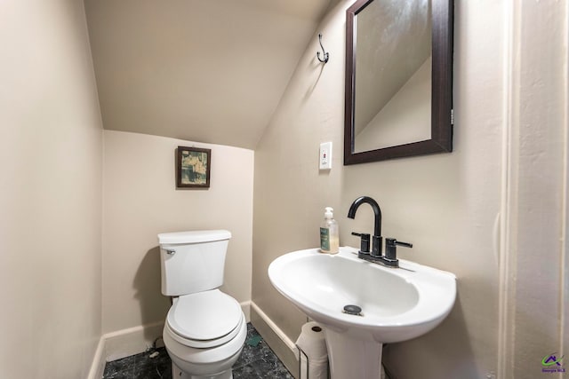 bathroom featuring toilet, sink, and vaulted ceiling