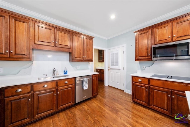 kitchen with ornamental molding, light hardwood / wood-style flooring, stainless steel appliances, and sink