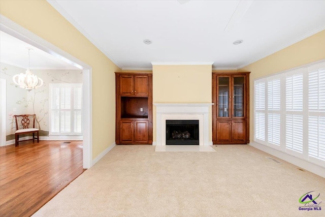 unfurnished living room with light hardwood / wood-style floors, ornamental molding, and a chandelier