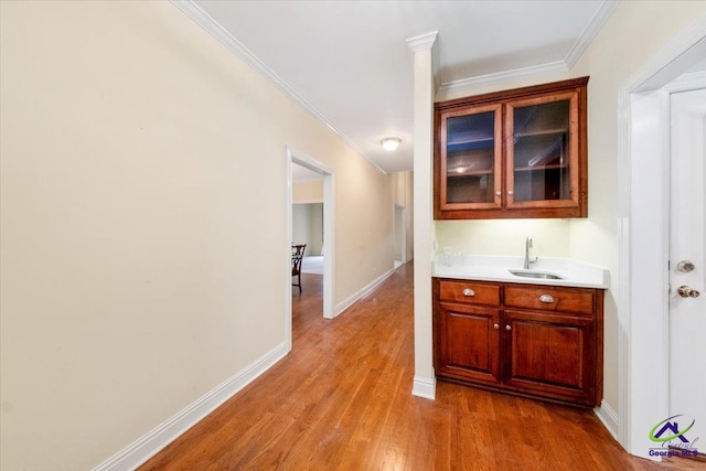 bar featuring sink, light hardwood / wood-style floors, and ornamental molding