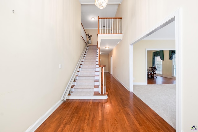 stairway with a towering ceiling, hardwood / wood-style flooring, and crown molding