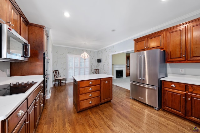 kitchen featuring crown molding, hanging light fixtures, hardwood / wood-style flooring, a notable chandelier, and stainless steel appliances