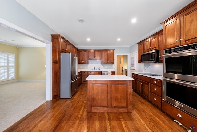 kitchen with sink, dark wood-type flooring, stainless steel appliances, crown molding, and a kitchen island