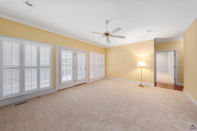 spare room featuring ceiling fan, light colored carpet, and crown molding