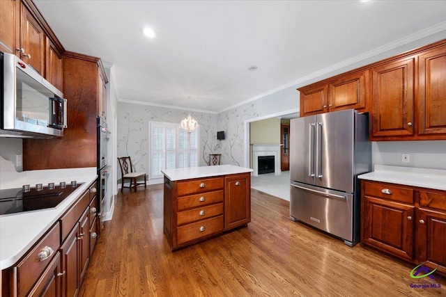 kitchen featuring hardwood / wood-style floors, decorative light fixtures, crown molding, and appliances with stainless steel finishes