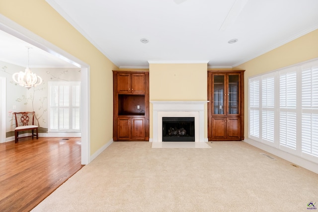 unfurnished living room with light wood-type flooring, crown molding, and a notable chandelier