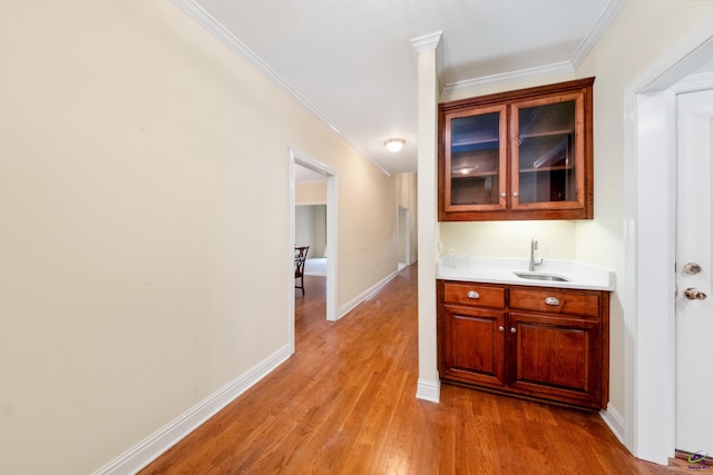 bar with ornamental molding, sink, and light hardwood / wood-style flooring