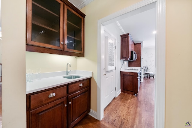 bar featuring stove, dark hardwood / wood-style floors, crown molding, and sink