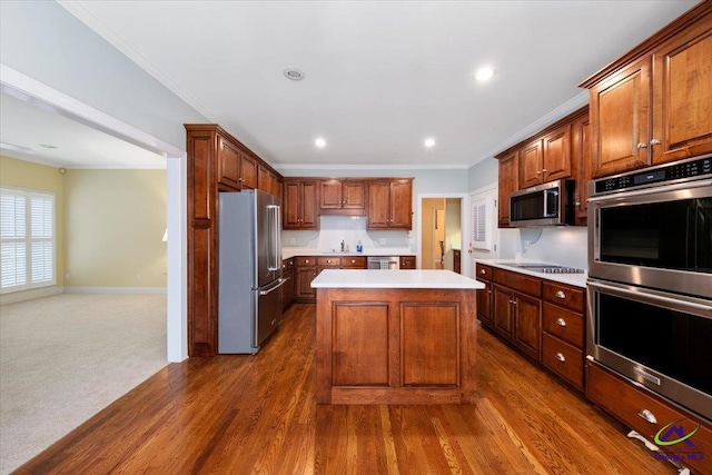 kitchen with dark hardwood / wood-style flooring, stainless steel appliances, crown molding, sink, and a kitchen island