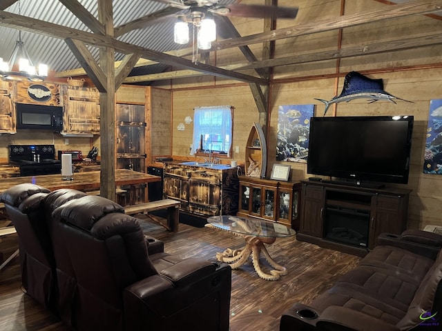 living room featuring vaulted ceiling with beams, hardwood / wood-style floors, ceiling fan, a fireplace, and wood walls