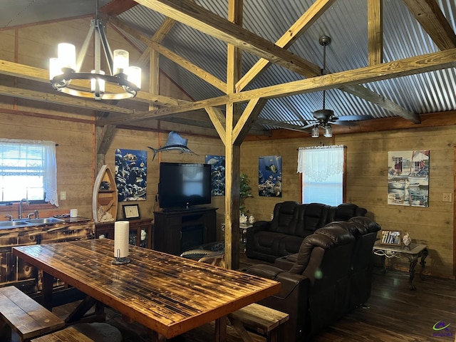 living room with high vaulted ceiling, wood walls, sink, and ceiling fan with notable chandelier