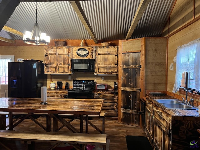 kitchen with sink, black appliances, pendant lighting, and wooden walls