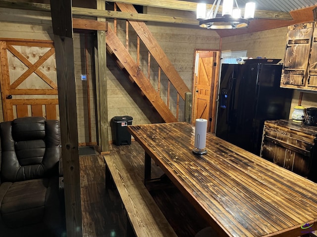 interior space featuring wood walls, a chandelier, pendant lighting, and black fridge