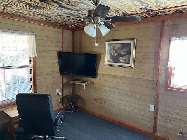 home office featuring ceiling fan, a healthy amount of sunlight, carpet, and wooden walls