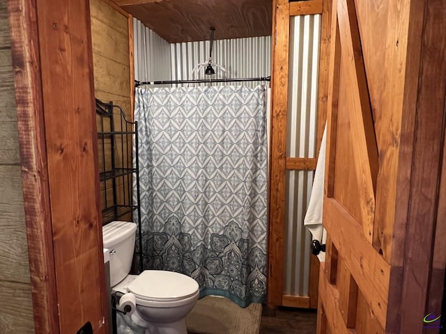 bathroom with toilet, wood walls, and curtained shower