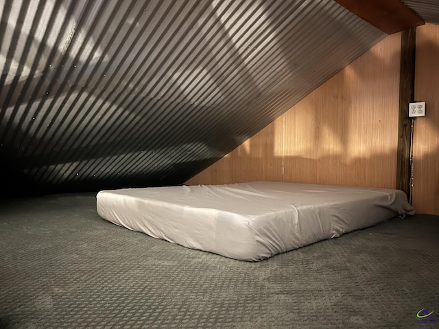 unfurnished bedroom featuring wood walls, carpet, and vaulted ceiling