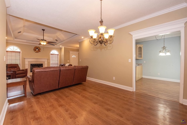 living room featuring ornamental molding, wood-type flooring, a tray ceiling, and ceiling fan with notable chandelier