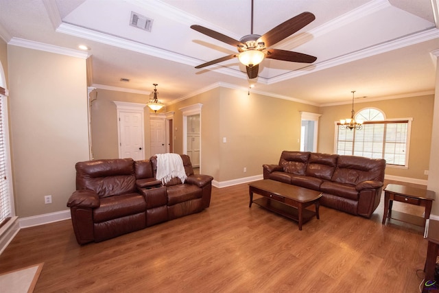 living room featuring hardwood / wood-style floors, crown molding, and a raised ceiling