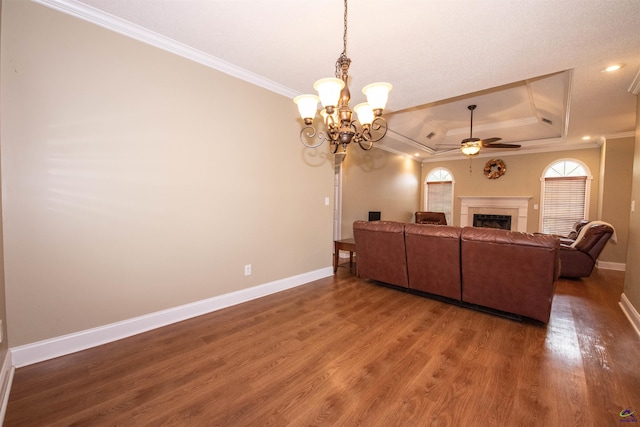 living room featuring crown molding, a raised ceiling, dark hardwood / wood-style flooring, and ceiling fan with notable chandelier